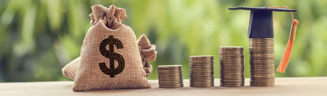 Stacks of coins growing increasingly taller with a graduation cap on top of the tallest one